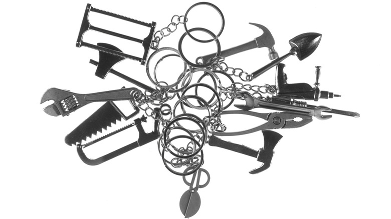 Pile of small tool-shaped keychain charms on a white background.