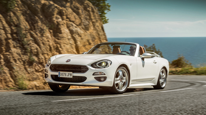 The Fiat 124 Spider with retro wheels on the move on a mountain road, front 3/4 view