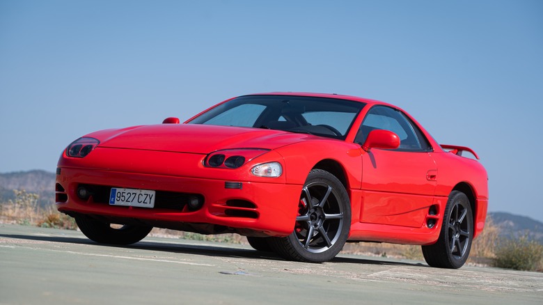 A red Mitsubishi 3000GT with aftermarket wheels, front 3/4 view