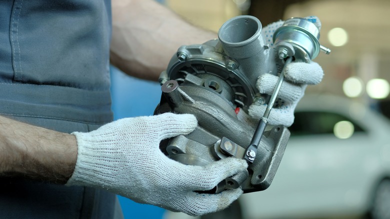 A mechanic holding a turbocharger