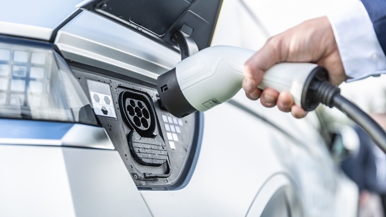 Person plugging in electric vehicle charger