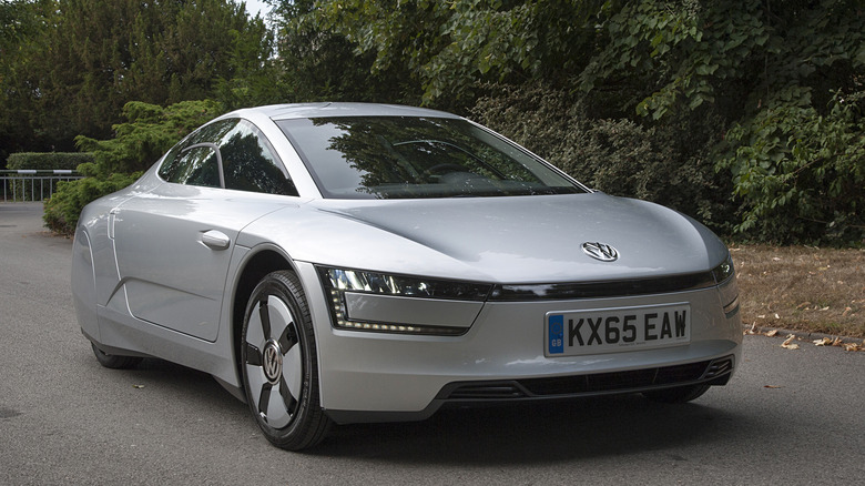 The Volkswagen XL1 in silver on a backroad, front 3/4 view