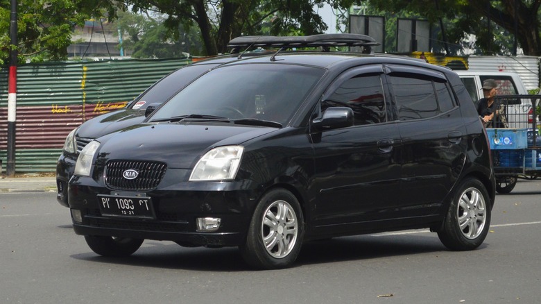 A Kia Picanto in black driving, front 3/4 view