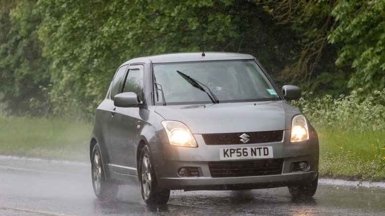 A 2006 Suzuki Swift driving in the rain, front view