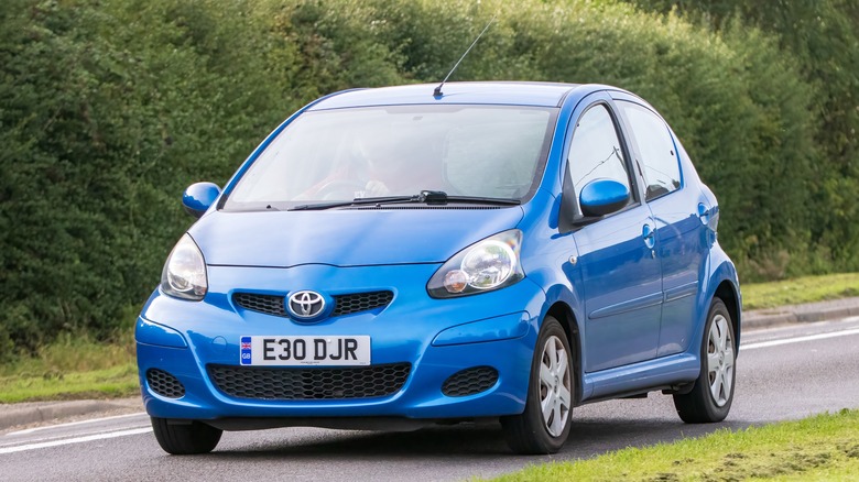 A first generation Toyota Aygo in blue on the road, front 3/4 view