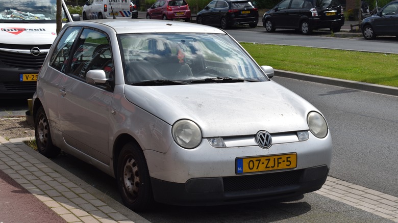 The Volkswagen Lupo 3L in silver, street parked, front 3/4 view