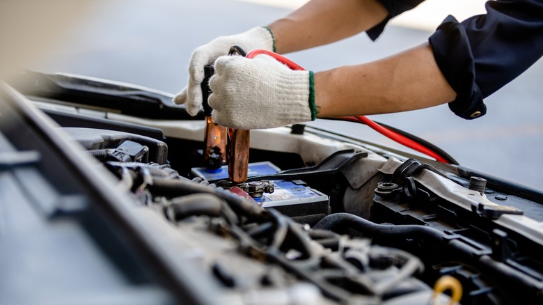 Person attaching jumper cables to a car battery