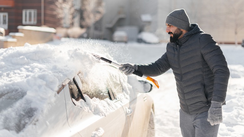 Man scraping snow off car