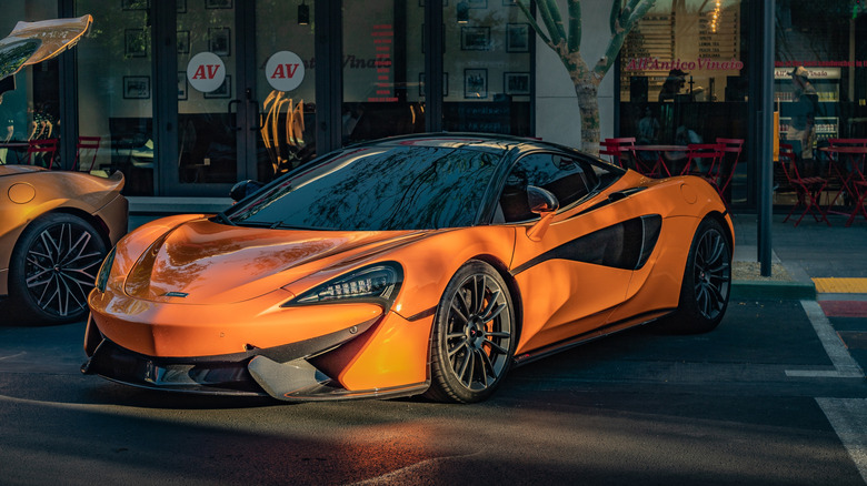 An orange McLaren 570S in the sunset, front 3/4 view