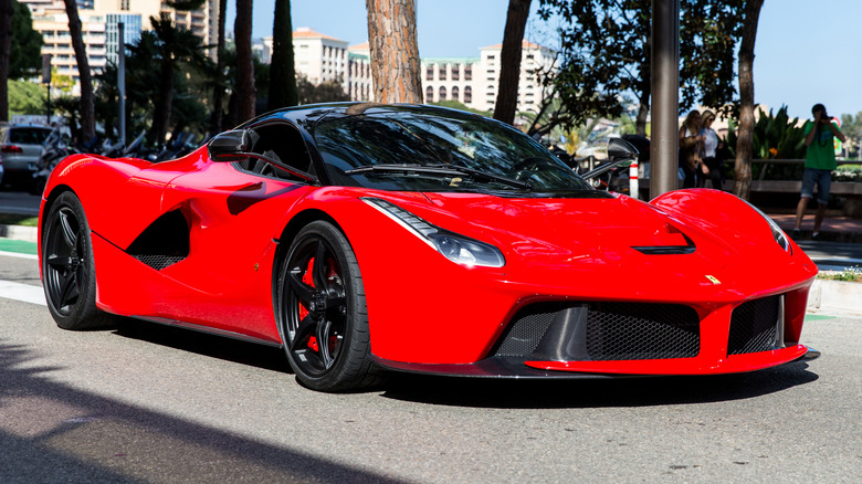 A red Ferrari LaFerrari is parked near trees.