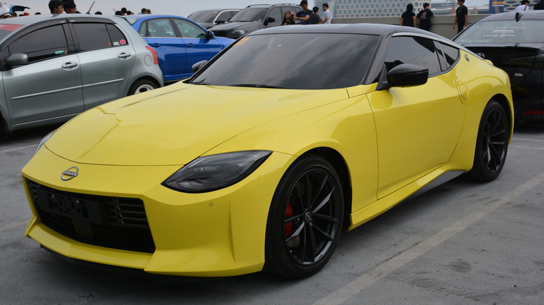 A new Nissan Z in yellow at a parking lot, front 3/4 view