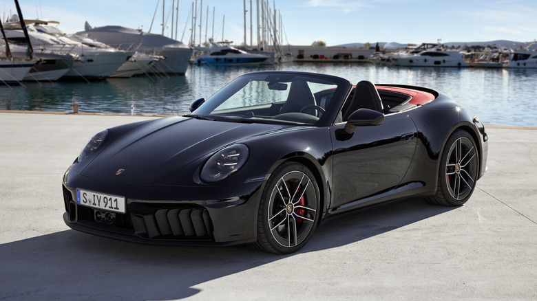 The 992.2 Porsche 911 Carrera GTS Cabriolet, black with red roof, front 3/4 view, roof down