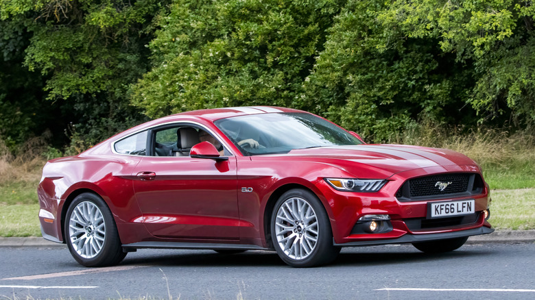 A red S550 Ford Mustang GT on the move, front 3/4 view, UK plates