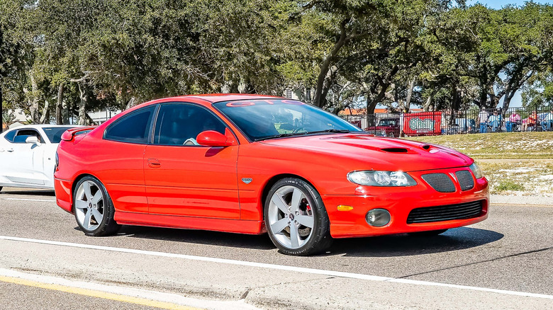 A bright red Pontiac GTO on the move, front 3/4 view