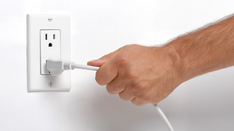 Man pulling extension cord out of outlet