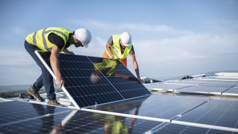 Two people installing a solar panel