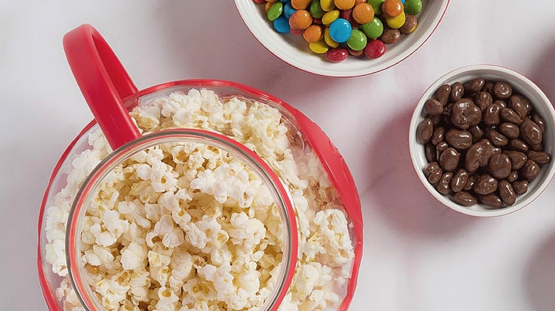 An Ecolution Micro-Pop Popcorn Popper sitting on a table next to some other snacks.