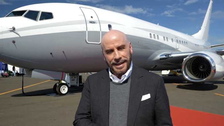 John Travolta standing in front of private jet