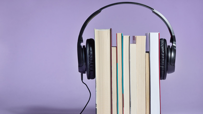 Stack of books with headphones, purple background