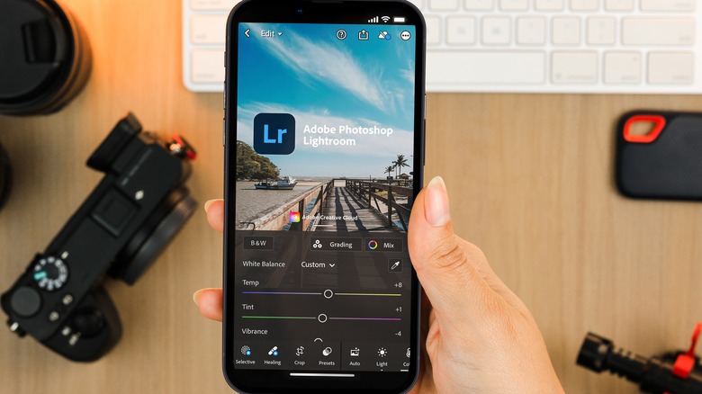 Adobe Lightroom app on smartphone over desk