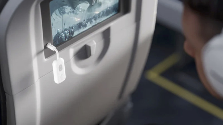 A man on a flight using the AirFly to listen wirelessly through his headphones.