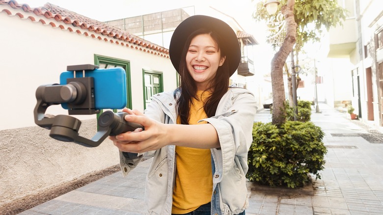 An Asian woman using a gimbal to stabilize her smartphone.