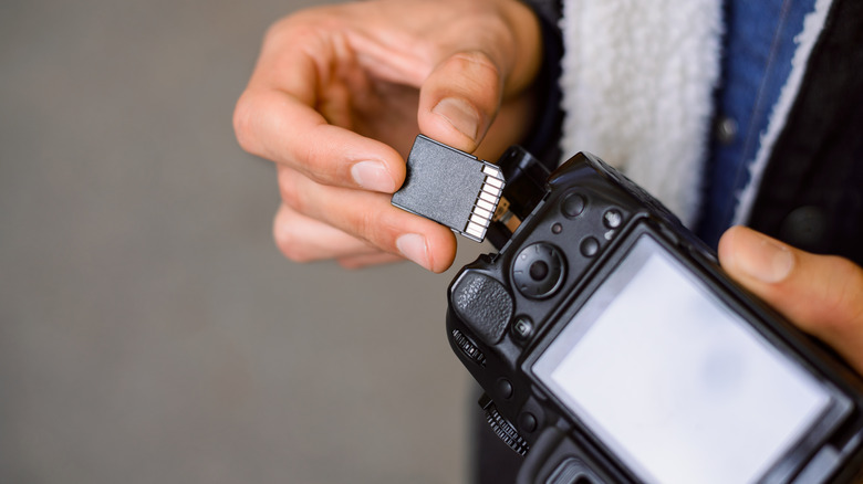 A photographer inserting a storage card into his camera.