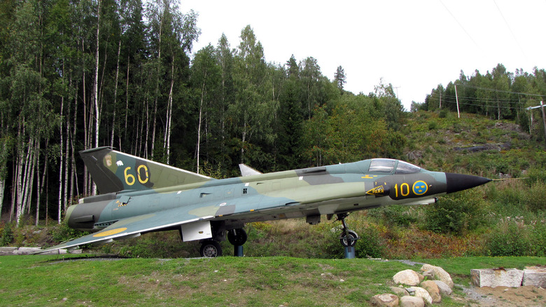 Saab J 35 on display with trees in background 