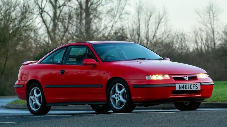 A Vauxhall Calibra in red driving, front 3/4 view