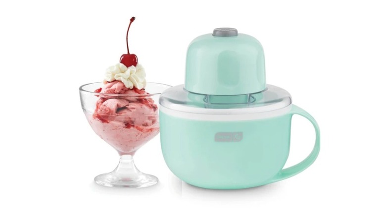 Mint green mug with churning motor on the top beside a cup of pink frozen dessert