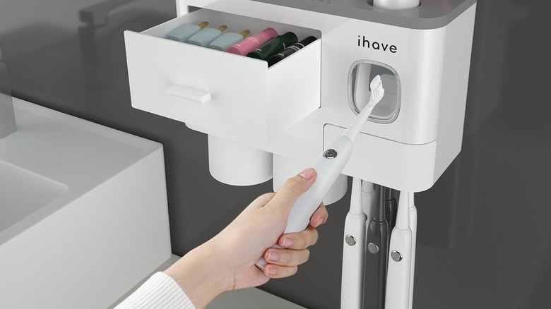 Hand holding a toothbrush inside a dispenser opening