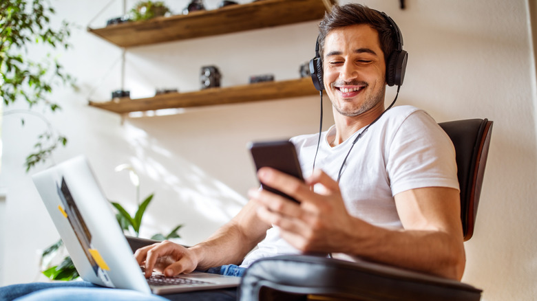 Man wearing wired headphones smiling at a smart phone