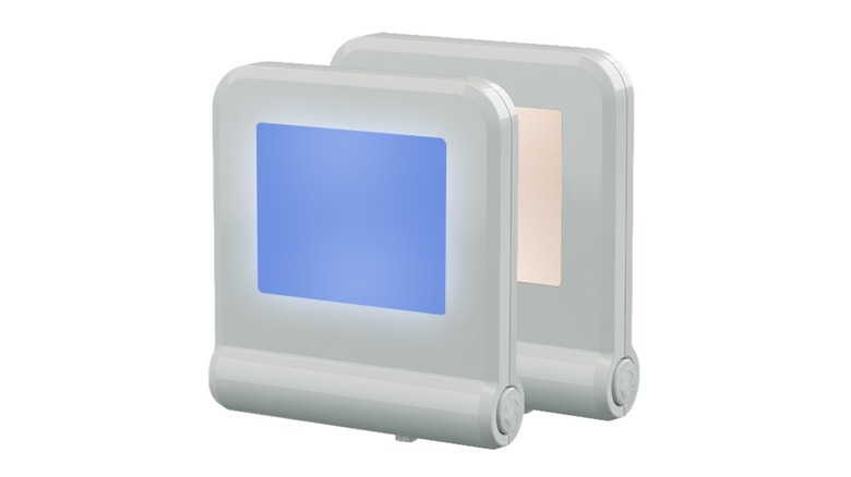 White square night light with a blue face in front of a similar nightlight with a pink face