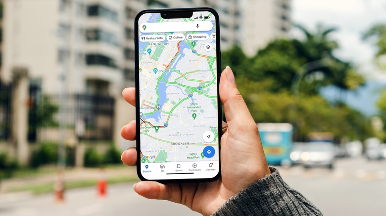 A woman holding a phone showing a map on Google Maps