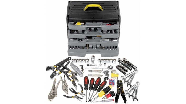 Assortment of basic tools like screwdrivers, wrenches, and pliers in front of a coordinating drawer-style case