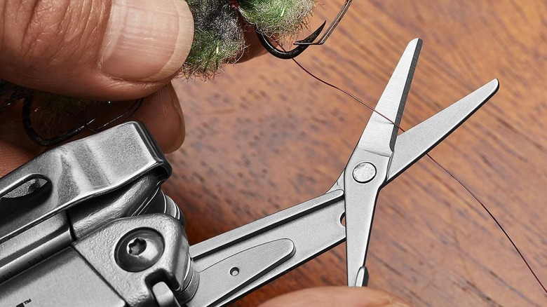 Silver multi-tool cutting fishing line attached to a hook