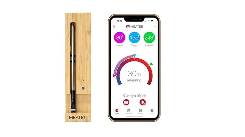 Slender pen-like meat thermometer beside a phone showing a temperature reading app