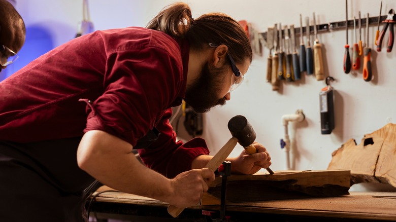 Person using a mallet and chisel on raw wood