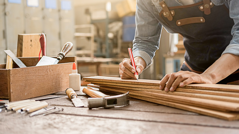 Carpenter working with equipment on wooden table in carpentry shop