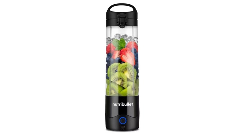 Tall slender blender filled with fruits and ice