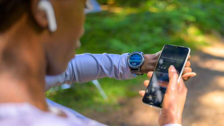 woman using phone and smartwatch for fitness