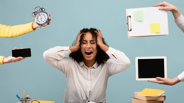 woman frustrated with tasks, devices, and clocks at her desk