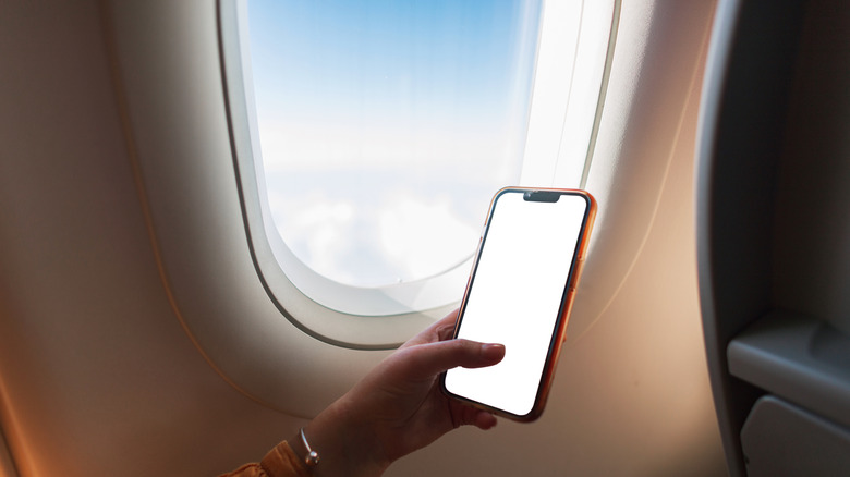 Person using smartphone on passenger jet