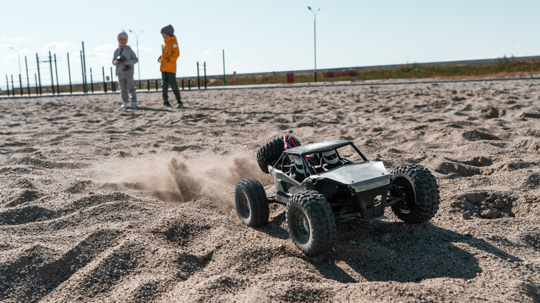 An off-road RC car tearing over sand.