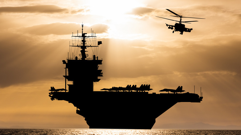 An aircraft carrier and helicopter from behind