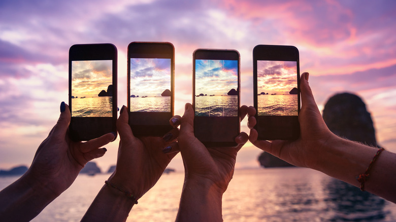 Four friends taking sunset photos