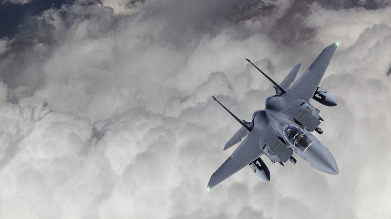 F-15 fighter jet flying over clouds