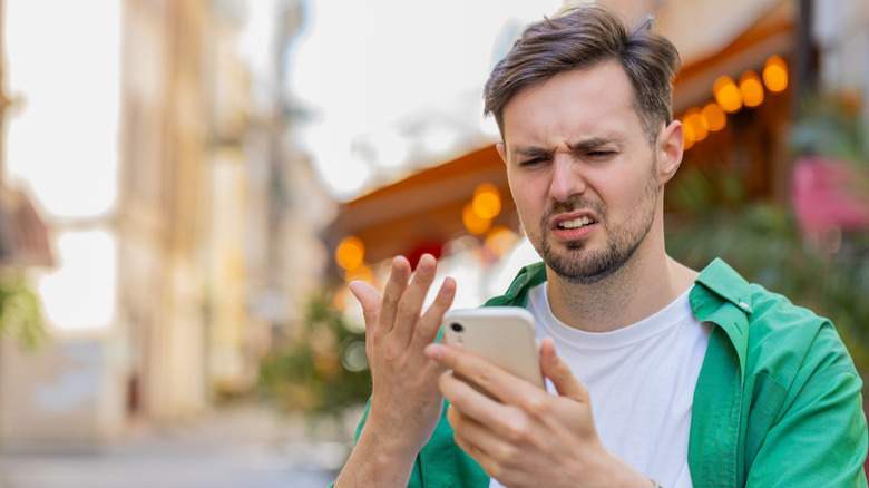 white male looking at his smartphone in confusion
