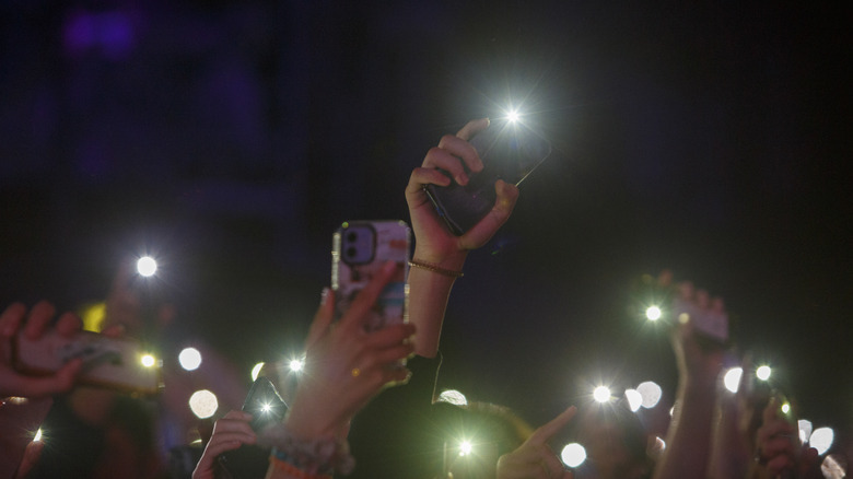 people holding smartphones up with flash on