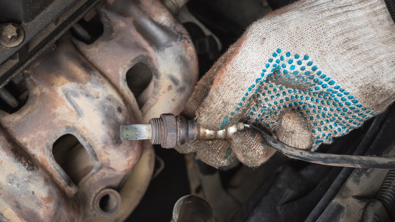 Person pulling out car engine sensor